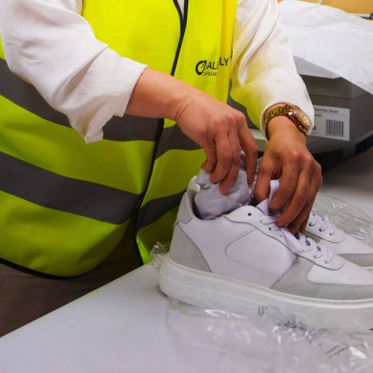 Eine Mitarbeiterin in einem Lager, die ein Paar Schuhe verpackt